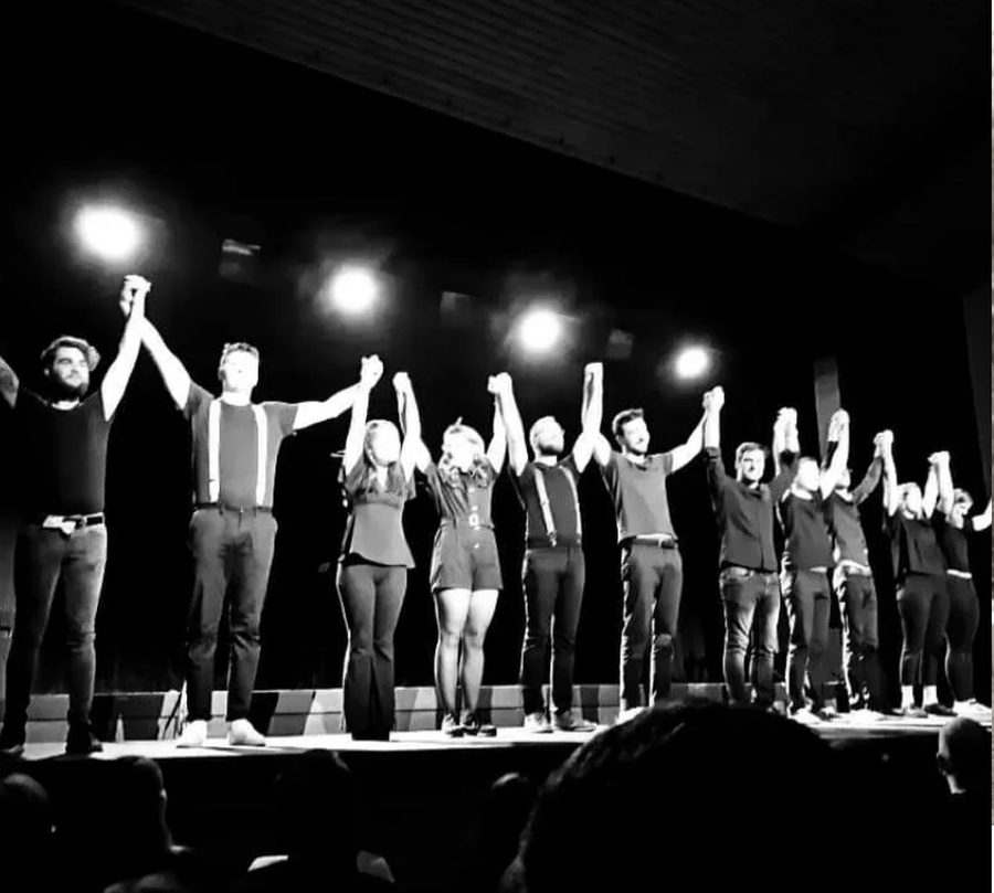 La troupe sur scène, bras levés, saluant le public