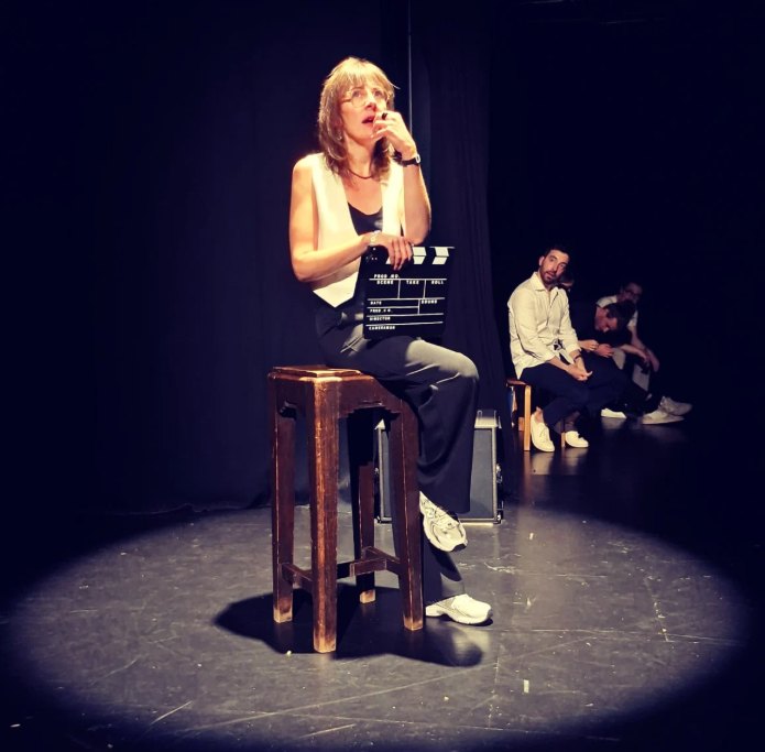 Comédienne de La Confrérire seule en scène sur un tabouret pendant un spectacle d'impro à Liège